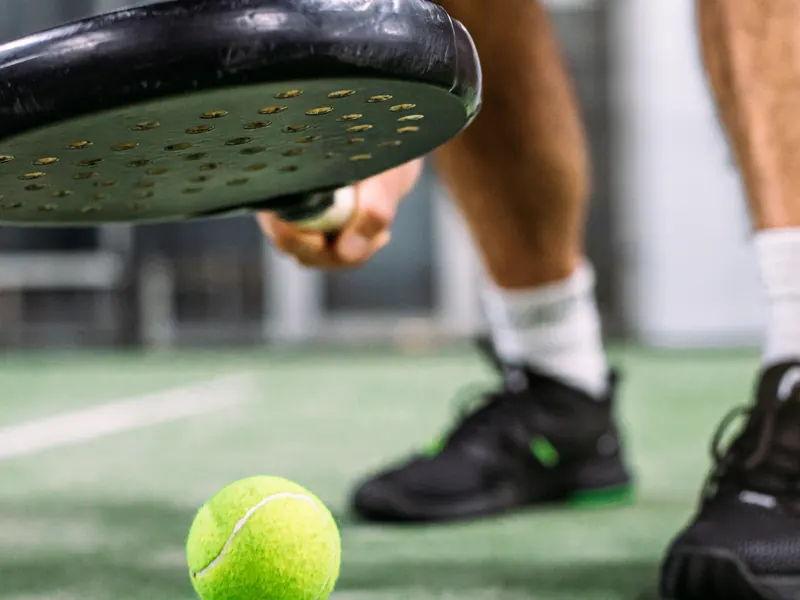 Pala y pelota en pista, con el overgrip visible en la empuñadura